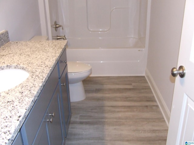 full bath with shower / bathtub combination, toilet, vanity, wood finished floors, and baseboards
