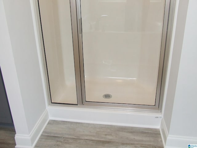 full bathroom featuring a stall shower, wood finished floors, and baseboards