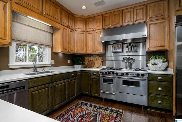 kitchen featuring high end appliances, dark wood finished floors, a sink, light countertops, and under cabinet range hood