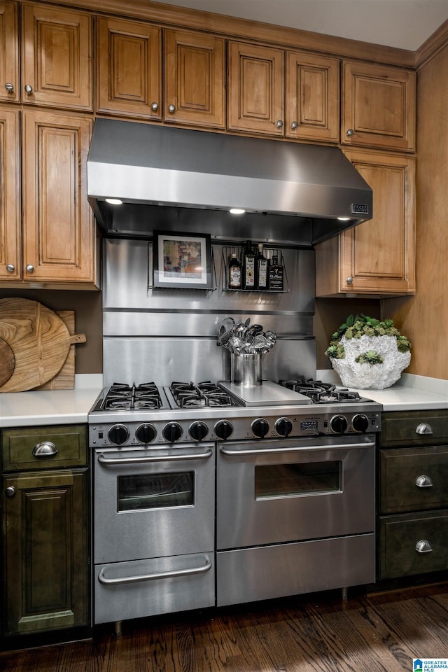 kitchen featuring dark wood finished floors, range with two ovens, light countertops, under cabinet range hood, and brown cabinets