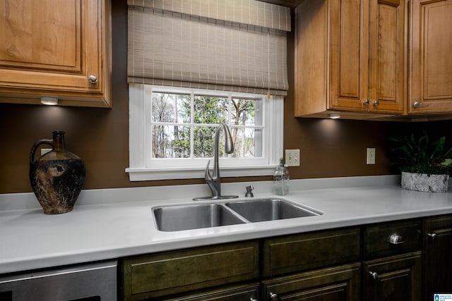 kitchen with dishwasher, light countertops, brown cabinetry, and a sink