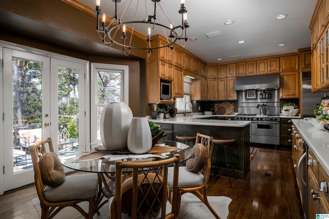 kitchen featuring brown cabinets, under cabinet range hood, premium appliances, dark wood finished floors, and light countertops