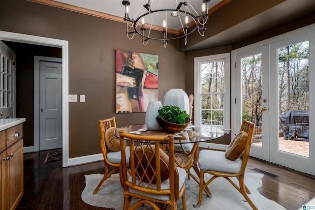 dining area with french doors, dark wood-type flooring, a chandelier, and crown molding