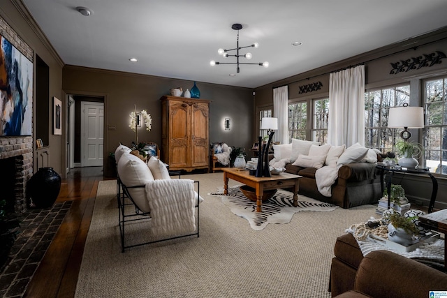 living area featuring hardwood / wood-style floors, an inviting chandelier, recessed lighting, ornamental molding, and a brick fireplace