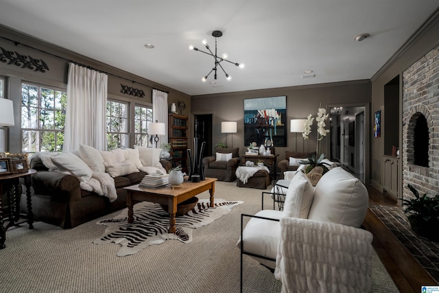 living room featuring a chandelier, wood finished floors, a brick fireplace, and ornamental molding