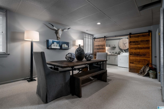 office space with a paneled ceiling, a barn door, light carpet, and independent washer and dryer