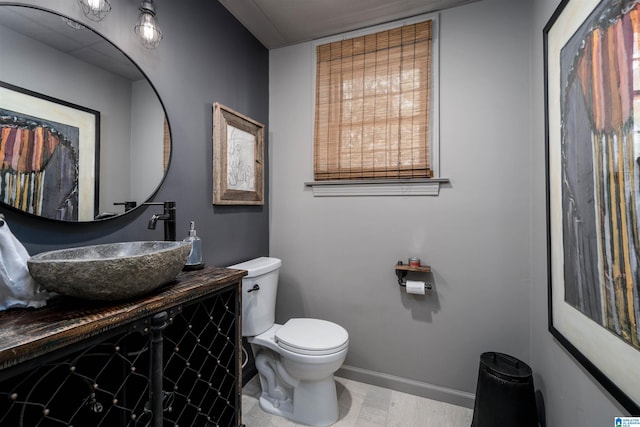 bathroom with toilet, vanity, and baseboards