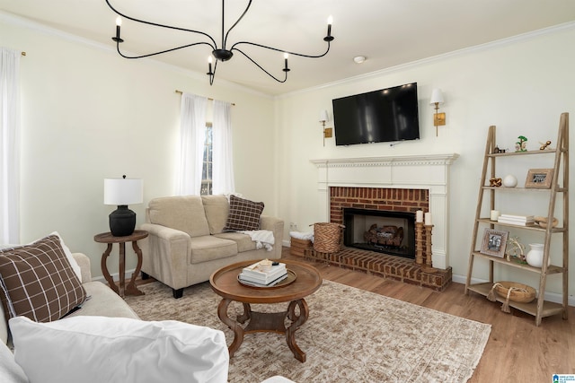 living room with wood finished floors, baseboards, an inviting chandelier, a fireplace, and ornamental molding