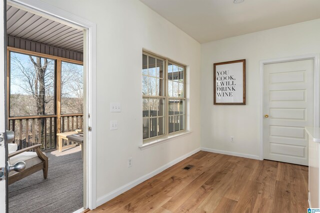 doorway with baseboards, visible vents, and light wood-type flooring