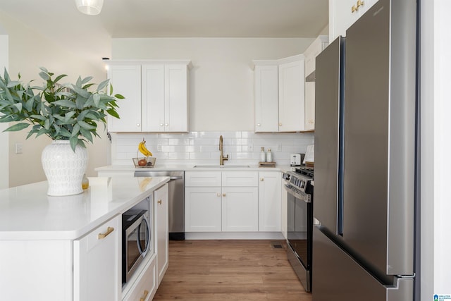 kitchen with a sink, stainless steel appliances, decorative backsplash, and light countertops