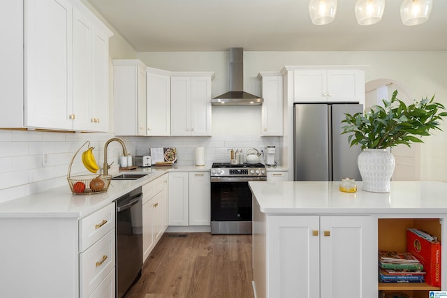 kitchen featuring a sink, decorative backsplash, light countertops, appliances with stainless steel finishes, and wall chimney range hood