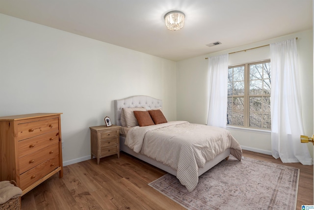 bedroom featuring visible vents, baseboards, and wood finished floors