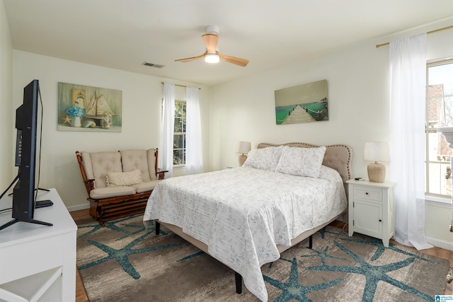 bedroom featuring visible vents, a ceiling fan, baseboards, and wood finished floors