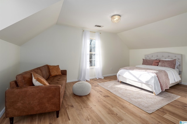 bedroom with lofted ceiling, baseboards, light wood-type flooring, and visible vents