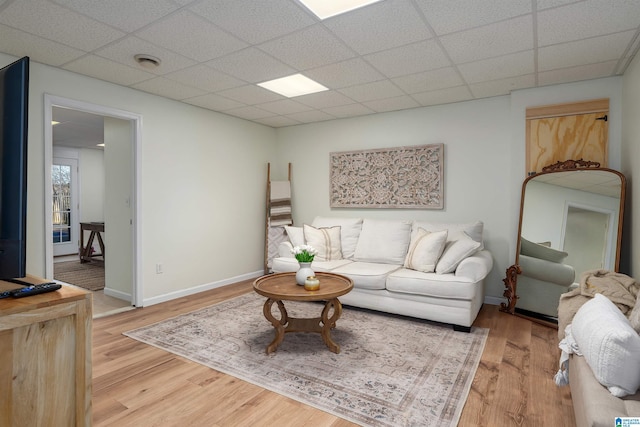 living room featuring light wood-style flooring, a paneled ceiling, and baseboards