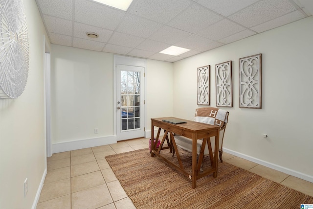 dining space featuring light tile patterned floors, a paneled ceiling, and baseboards