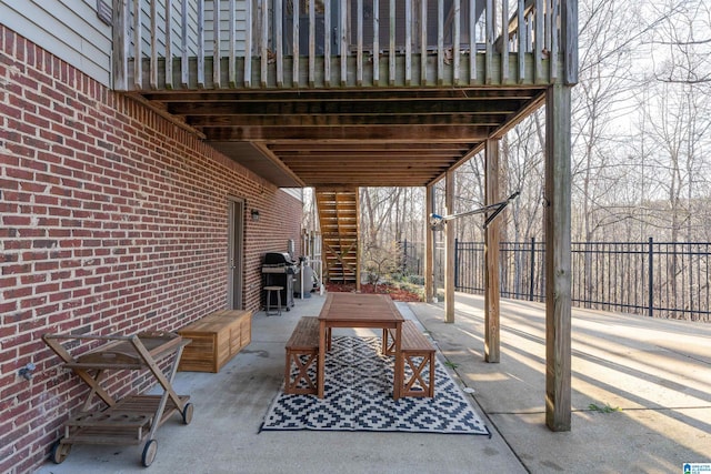 view of patio featuring stairs, outdoor dining area, fence, and grilling area