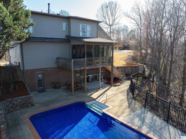 rear view of house featuring brick siding, a fenced in pool, a fenced backyard, a sunroom, and a patio