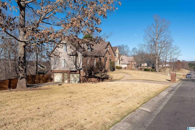 exterior space featuring a garage, brick siding, a front lawn, and fence