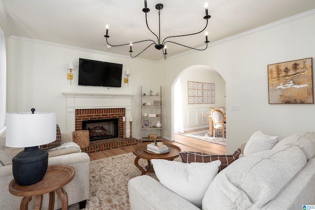 living area featuring arched walkways, a fireplace, crown molding, and wood finished floors