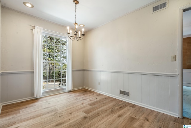 spare room with visible vents, wood finished floors, and a wainscoted wall