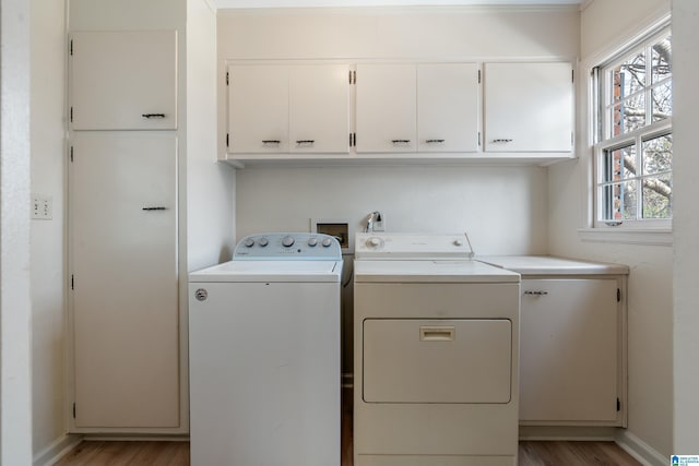 laundry area featuring baseboards, cabinet space, light wood-style floors, and independent washer and dryer