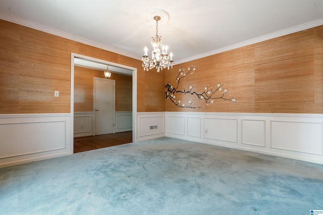 carpeted empty room with crown molding, wainscoting, visible vents, and a chandelier