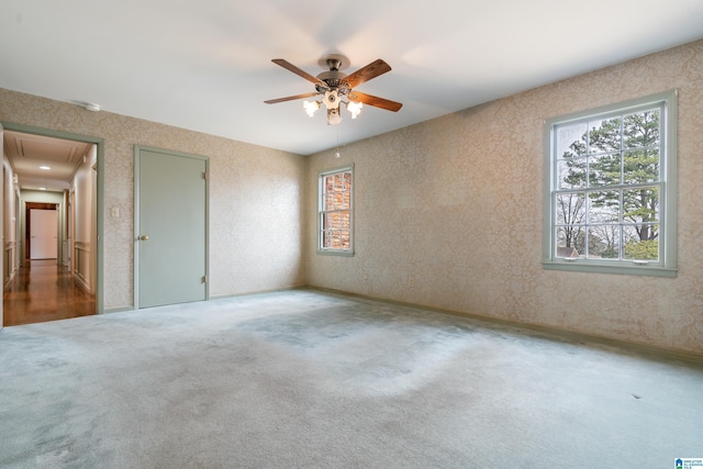 unfurnished bedroom with attic access, ceiling fan, and carpet flooring