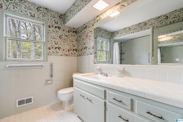 bathroom with visible vents, wallpapered walls, wainscoting, a shower with curtain, and tile walls