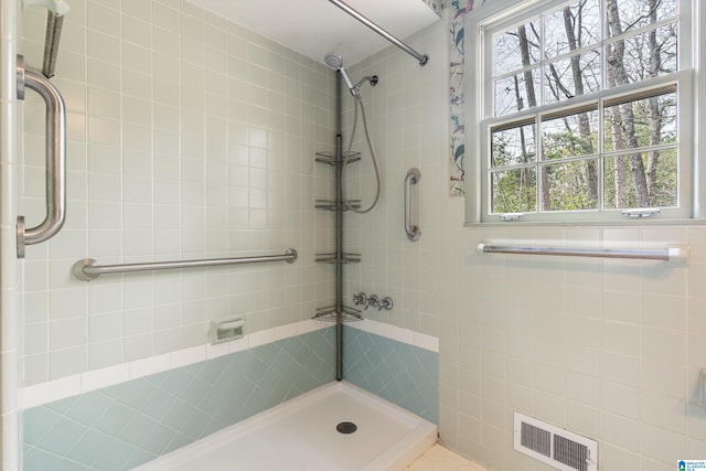 full bath with visible vents and a tile shower