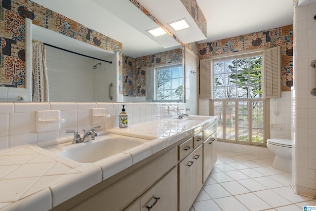 full bath featuring wallpapered walls, tile walls, toilet, and double vanity