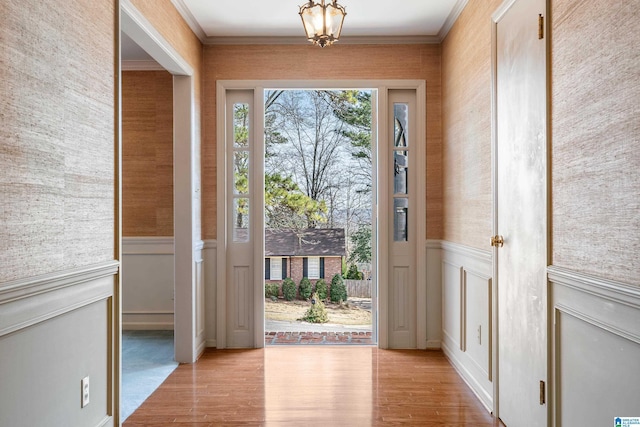 foyer featuring a wainscoted wall, wood finished floors, and ornamental molding