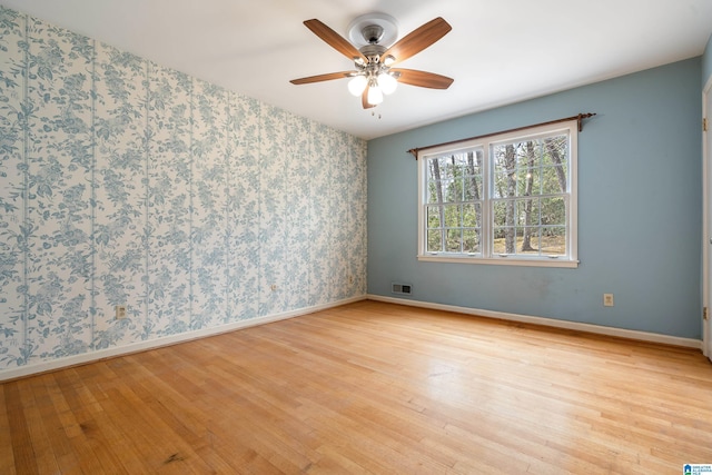 unfurnished room featuring wallpapered walls, visible vents, light wood-style floors, and baseboards