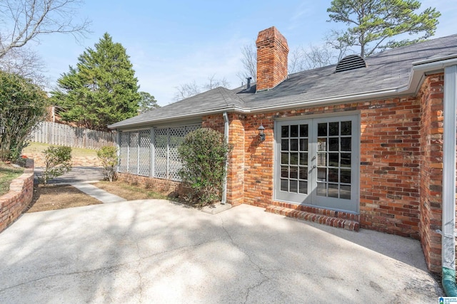 back of house featuring fence, a chimney, french doors, a patio area, and brick siding