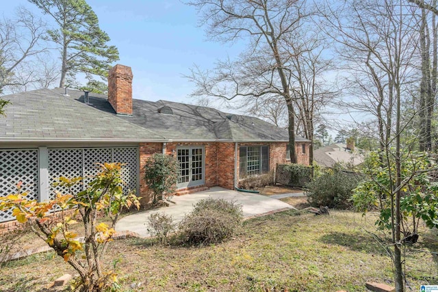 rear view of house with a patio, brick siding, and a chimney