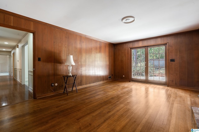 empty room with wood finished floors, baseboards, and ornamental molding