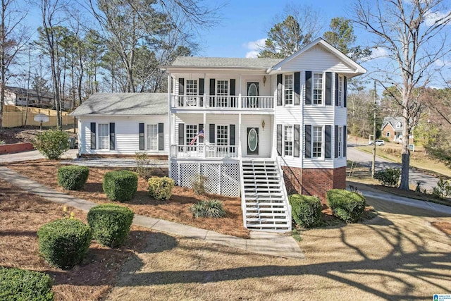 colonial-style house with covered porch, brick siding, stairway, and a balcony