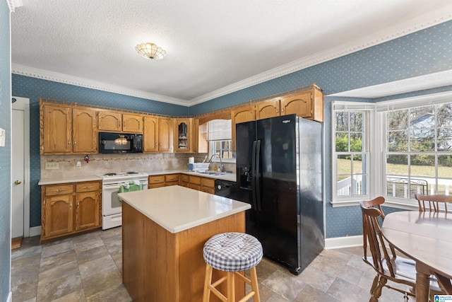 kitchen with wallpapered walls, baseboards, light countertops, black appliances, and a sink