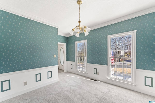 spare room with a notable chandelier, wainscoting, carpet flooring, a textured ceiling, and wallpapered walls