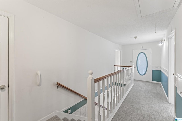 hallway with attic access, baseboards, carpet flooring, and an upstairs landing