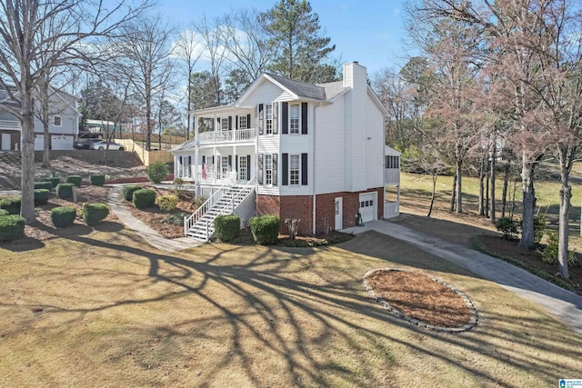 view of front of property with a chimney, a porch, stairway, a balcony, and driveway