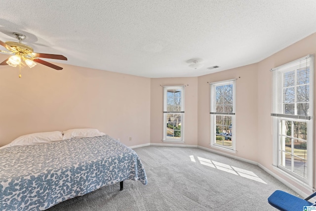 bedroom with baseboards, visible vents, ceiling fan, a textured ceiling, and carpet flooring