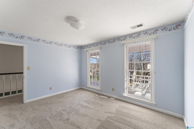 carpeted empty room featuring a textured ceiling, visible vents, and baseboards