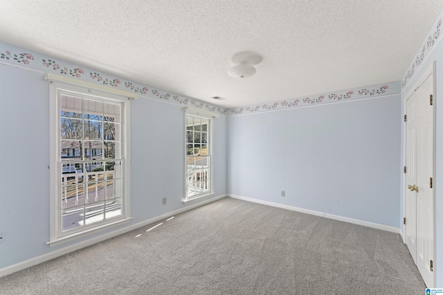 spare room with carpet, visible vents, baseboards, and a textured ceiling