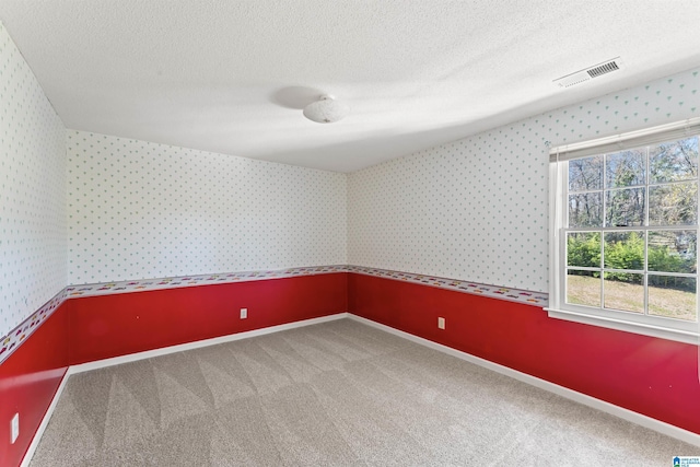 spare room featuring carpet floors, wallpapered walls, baseboards, and a textured ceiling