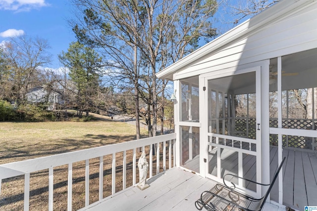 wooden terrace featuring a sunroom and a lawn