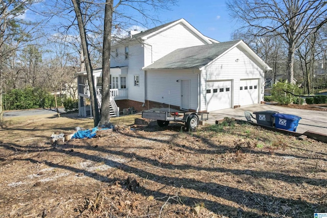 view of property exterior featuring concrete driveway, an attached garage, and a sunroom