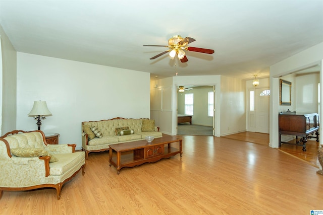 living room with baseboards, a ceiling fan, and wood finished floors