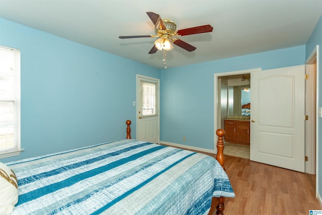 bedroom with light wood finished floors, ensuite bath, a ceiling fan, and baseboards