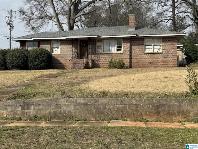 view of front of property featuring brick siding, a chimney, a front yard, and a shingled roof